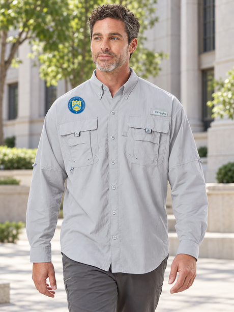 BEP men's Columbia Bahama II long-sleeve shirt in Cool Grey, with the product's original Bureau of Engraving and Printing seal above the right chest pocket, at an administrative office campus.